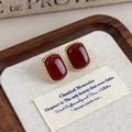Dettaglio degli orecchini vintage rosso scuro con montatura dorata ritorta su vassoio in legno - Rosso Scuro (Stile Principale)