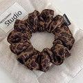 Suede leopard print hair scrunchie with handmade label on beige canvas background - Leopard Print (Main Image)