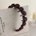 Nahaufnahme eines braunen Strickstirnbands mit Perlen und Strass auf einem Display - Kaffee (27663C)