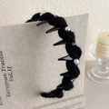 Detailansicht eines schwarzen Strickstirnbands mit Perlen und Strass auf einem Buch - Schwarz (27663D)