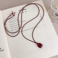Primer plano del colgante rojo oscuro mate sobre fondo de libro antiguo artístico - Colgante Rojo
