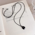 Detailed close-up of a black stone pendant necklace resting on a literary book page - Black Pendant