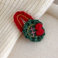 Dettaglio del fermaglio per capelli natalizio lavorato a maglia con motivo a ghirlanda - Disco Verde Nodo Rosso (27706D)