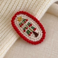 Close-up of handmade knit Christmas tree hair clip with red scalloped edges and gold star - Beige Red Border (27706K)