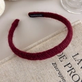 Detailed close-up of dark burgundy knitted headband with a handmade label on fabric - Red