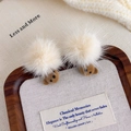 Detail of plush brown bear hair clips with cream pom-poms on a cozy autumn fabric background - Light Coffee