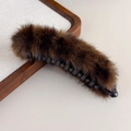 Détail d'une grande pince banane en fourrure marron foncé sur un plateau en bois - Style Léopard