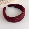 Detail eines weinroten Woll-Stirnbands mit goldenem Glitzerfaden und Handmade-Label - Fuchsie