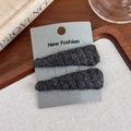 Close-up of black knitted wool hair clips on display card with warm vintage decor - Black (27652F)
