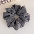 Gros plan d'un chouchou en tricot gris foncé avec des fils dorés brillants pour cheveux - Gris