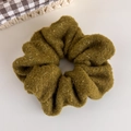 Détail d'un chouchou en maille vert olive avec fil doré scintillant et texture peluche - Vert