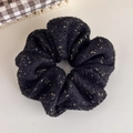 Gros plan détaillé sur un chouchou en tricot noir avec des fils dorés scintillants - Noir