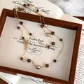Collana lunga vintage occhio di tigre e perle con chiusura OT dorata su sfondo libro retro - Stile Catena Oro Perla Occhio Di Tigre