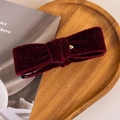 Close-up of burgundy velvet bow hair clip with silver glitter on wooden tray - Burgundy