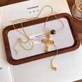 Dettaglio della collana croce in occhio di tigre con incisione dorata e strass ambra - Oro