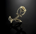 Detailed close-up of a hollow gold rose brooch with a mirrored reflection on black surface - Gold
