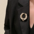 Elegante goldene Kranzbrosche mit weißen Perlen am schwarzen Revers, Luxus-Modestil - Goldener Weizenährenkreis Stil