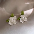 Élégantes boucles d'oreilles fleurs blanches avec feuilles vertes sur fond de soie champagne - Boucles d'Oreilles Clous Gardénia Blanc Perlé
