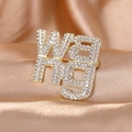 Golden WANG letter brooch with shimmering crystals on luxury silk fabric background - Gold