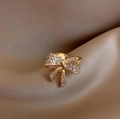 Elegant gold bow brooch with pavé rhinestones on luxury champagne satin background - Gold Bow Style