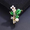 Dettaglio di spilla a foglia in smalto verde con perle e cristalli su base dorata - Stile Mughetto Foglia Verde