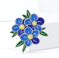 Macro di un'elegante spilla floreale in smalto con fiori blu e dettagli dorati - Blu
