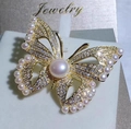 Vista macro de un broche de mariposa dorado con perlas y circonitas en tarjeta de joya - Dorado