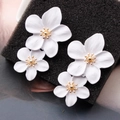 Detalle macro de pendientes de flores blancas en 3D con estambres metálicos dorados - Blanco