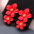 Detalle macro de pendientes de flores rojas de doble capa con estambres dorados finos - Rojo