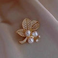 Eleganter Blatt-Brosche mit drei rosa Perlen und funkelnden Zirkonen auf Satinstoff - Goldenes Hohles Blatt