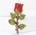 Spilla rosa con strass, petali rossi e foglie verdi su un blocco bianco pulito - Rosso