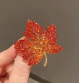 Détail macro d'une broche feuille d'érable rouge sertie de zircons dégradés dorés - Rouge