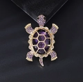 Macro shot of purple gemstone turtle brooch with sparkling gold crystal details - Purple