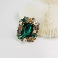 Dettaglio macro della spilla vintage smeraldo con perle bianche e pietre preziose - Verde