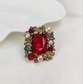Vista macro di una spilla vintage con cristallo rosso e perle bianche su ceramica - Rosso
