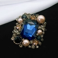Dettaglio macro della spilla vintage con gemma blu scuro e perle rosa cipria - Blu