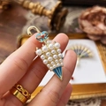 Golden umbrella brooch with white pearls, blue enamel bow and a red gemstone - Umbrella Shape
