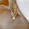 Eleganter Blatt-Anstecker aus Gold mit Diamanten und weißer Perle auf Seidenhintergrund - Goldene Blätter