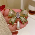 Dettaglio di una spilla a fiocco scintillante con pietre verdi e perla a goccia - Verde