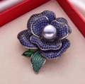 Macro detail of camellia brooch with purple pearl and blue crystals in a gift box - Blue