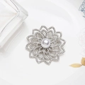 Spilla a fiore argentata con perla centrale e petali di cristallo su sfondo elegante - Argento