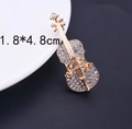 Primer plano detallado de un broche de violín dorado con pedrería y medidas 1,8x4,8 cm - Dorado