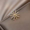 Gouden ster-broche met fonkelende zirkoon-kristallen op zijden achtergrond - Sterrenstraal Stijl (EH10524)