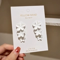 Close-up of white layered flower drop earrings with a matte texture on display card - White