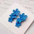 Dettaglio di orecchini a fiore blu opaco con perni in argento 925 su carta da esposizione - Blu lago