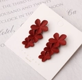 Detail view of red floral triple petal earrings with matte finish on silver needles - Red
