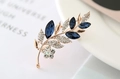 Dettaglio di una spilla a foglia con cristalli blu navy e finitura in oro rosa lucido - Blu