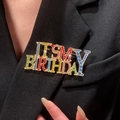 Détail de la broche colorée 'IT'S MY BIRTHDAY' en strass sur une veste de costume noire - Broche Multicolore (5829)