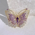 Détail macro d'une élégante broche papillon avec cristaux violets et filigrane doré - Style Papillon Or Violet