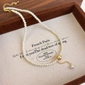 Detailed close-up of a minimalist pearl necklace with a brushed gold sphere in a box - Gold Style (27231A)
